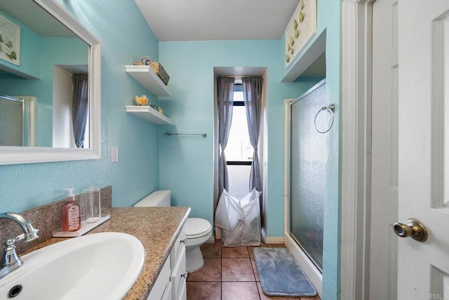 bathroom with vanity, toilet, tile patterned floors, and a shower with shower door