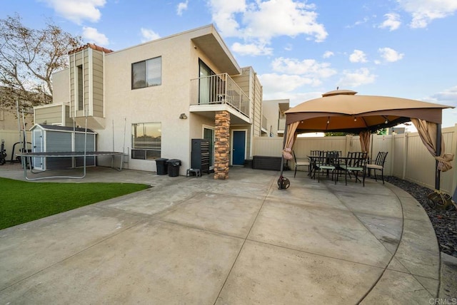 rear view of property with a shed, a gazebo, a patio area, and a balcony