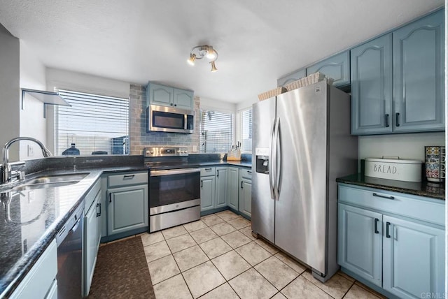 kitchen featuring tasteful backsplash, sink, dark stone counters, light tile patterned floors, and stainless steel appliances