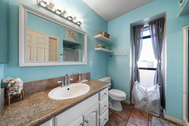 bathroom with tile patterned flooring, vanity, a shower with shower door, and toilet