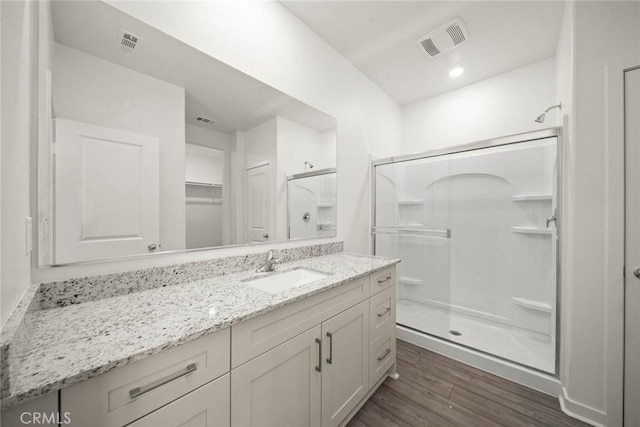 bathroom with hardwood / wood-style flooring, vanity, and a shower with shower door