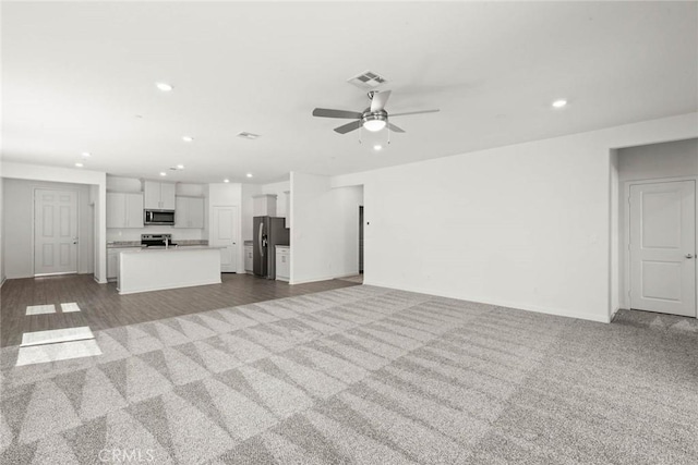 unfurnished living room with light colored carpet and ceiling fan