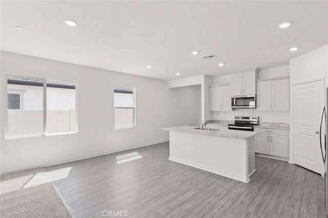 kitchen with sink, white cabinets, stainless steel appliances, a center island with sink, and light hardwood / wood-style flooring