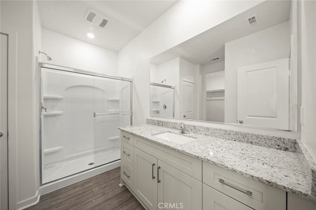 bathroom featuring hardwood / wood-style flooring, vanity, and an enclosed shower