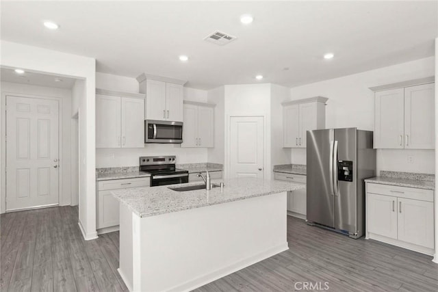 kitchen with sink, light stone counters, stainless steel appliances, a kitchen island with sink, and white cabinets