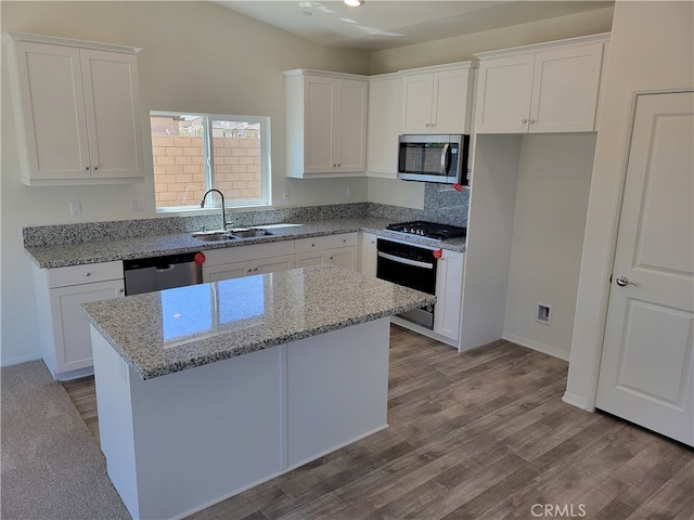 kitchen featuring stainless steel appliances, a kitchen island, a sink, and white cabinets