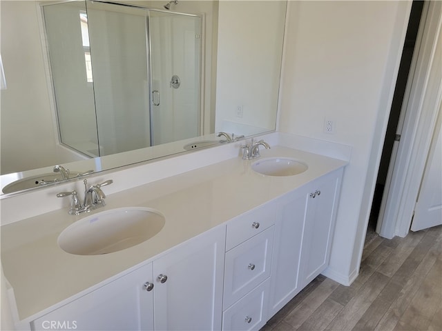 full bath featuring a stall shower, a sink, and wood finished floors