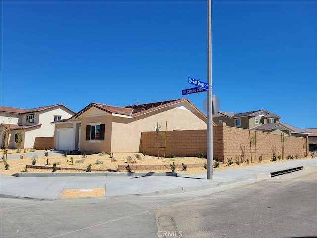 view of front facade featuring a garage, a residential view, fence, and stucco siding