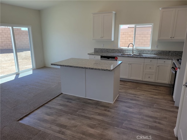 kitchen with sink, dark wood-type flooring, stove, light stone counters, and white cabinets