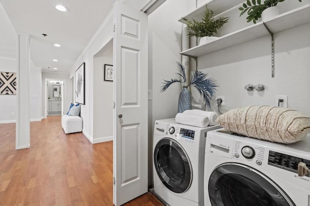 clothes washing area with independent washer and dryer, ornamental molding, and hardwood / wood-style floors