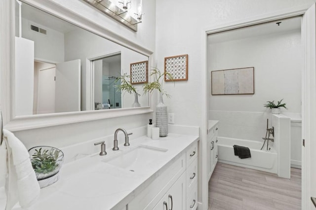 bathroom with vanity, a bath, and hardwood / wood-style flooring