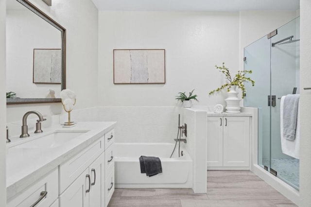 bathroom featuring hardwood / wood-style flooring, vanity, and separate shower and tub