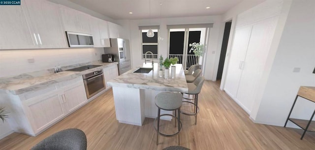 kitchen with pendant lighting, appliances with stainless steel finishes, a kitchen island with sink, and white cabinets