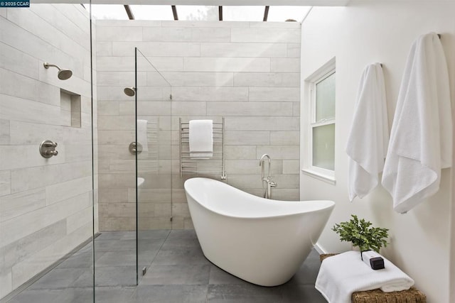 bathroom with shower with separate bathtub and tile walls