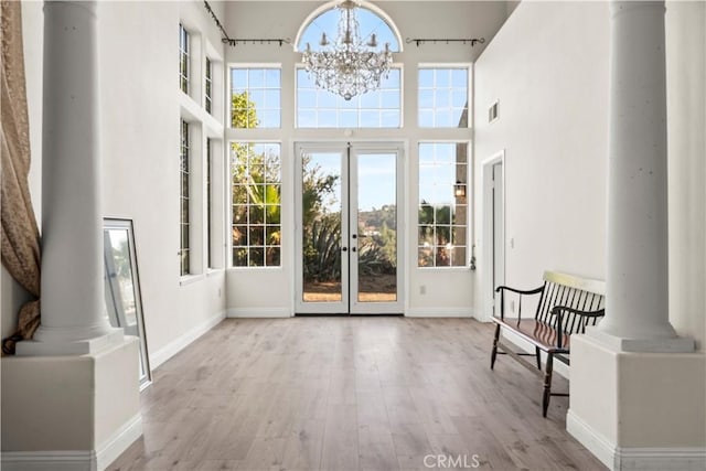 sunroom featuring ornate columns, an inviting chandelier, and french doors