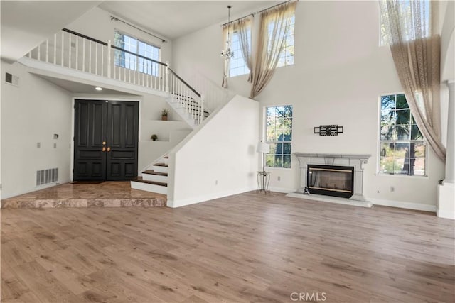 unfurnished living room with a fireplace, wood-type flooring, and a high ceiling