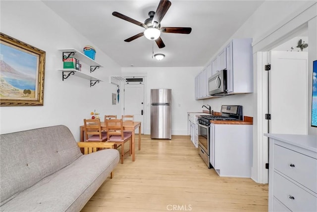 kitchen featuring sink, ceiling fan, appliances with stainless steel finishes, light hardwood / wood-style floors, and white cabinets