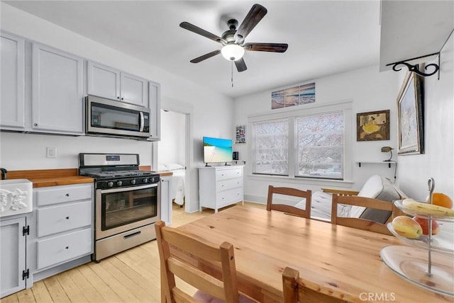 kitchen featuring ceiling fan, appliances with stainless steel finishes, wooden counters, and light wood-type flooring