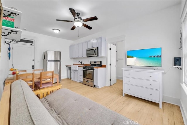 kitchen with white cabinetry, ceiling fan, stainless steel appliances, and light wood-type flooring