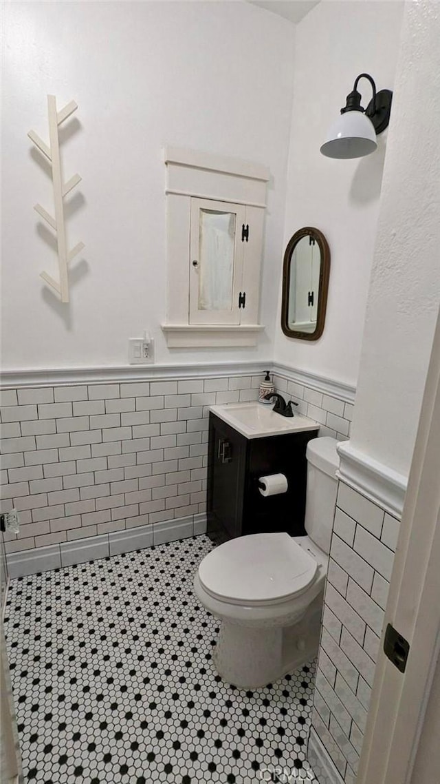 bathroom with tile patterned flooring, vanity, tile walls, and toilet