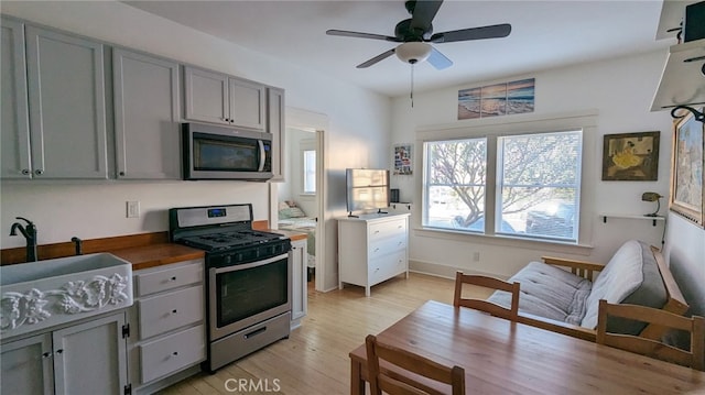 kitchen with sink, light hardwood / wood-style flooring, gray cabinets, ceiling fan, and stainless steel appliances