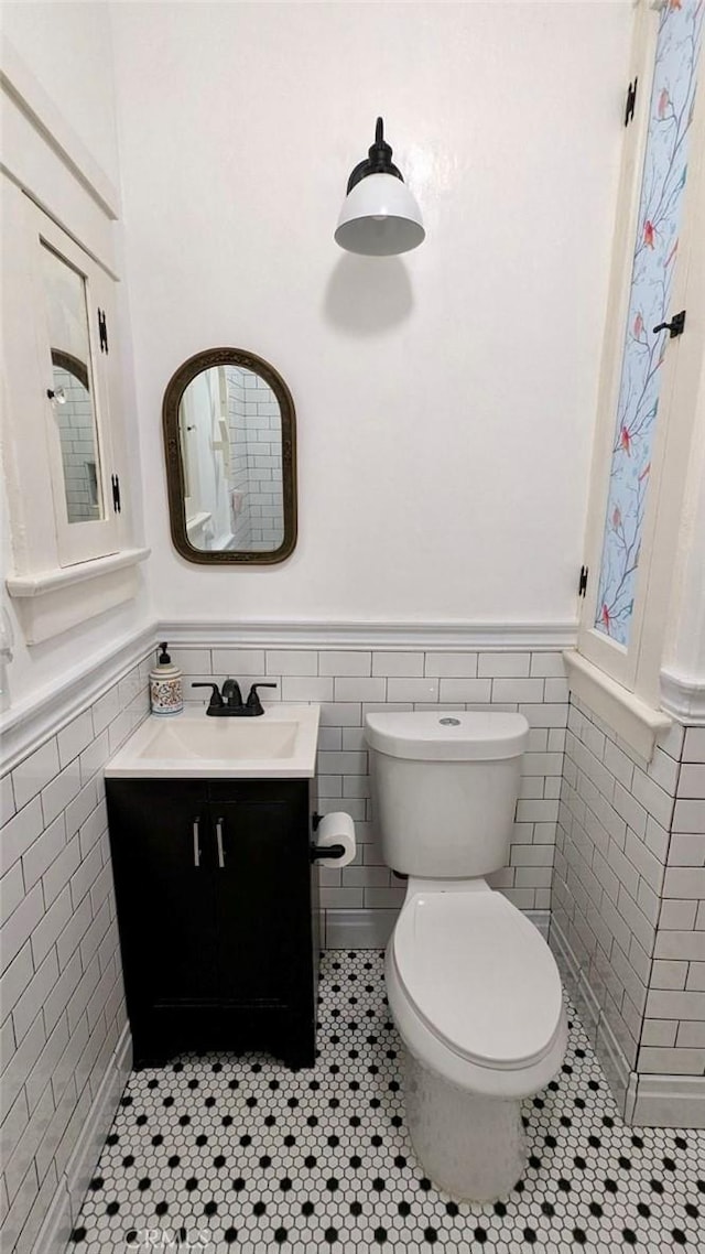 bathroom with vanity, tile walls, tile patterned floors, and toilet