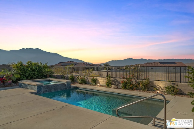 pool at dusk featuring an in ground hot tub and a mountain view