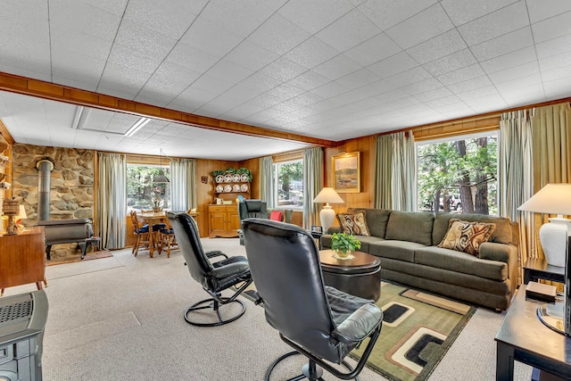 living room with wood walls, a wealth of natural light, carpet floors, and a wood stove