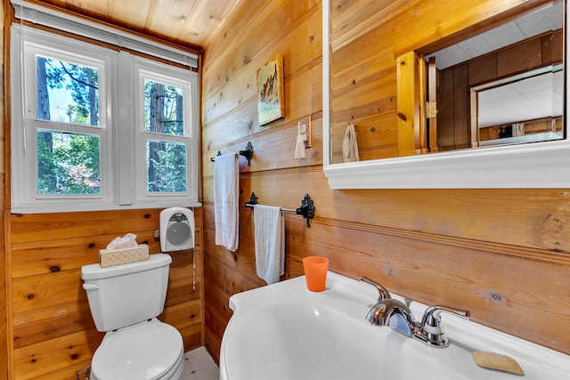 bathroom featuring toilet, wood ceiling, wooden walls, and sink