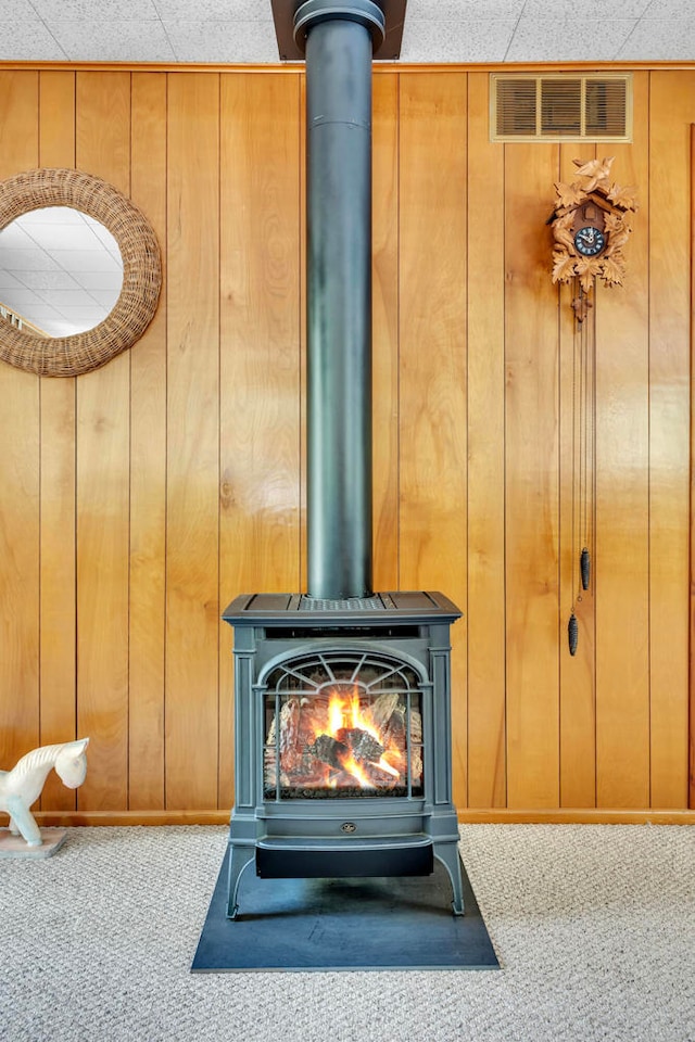 details featuring carpet floors, wood walls, and a wood stove