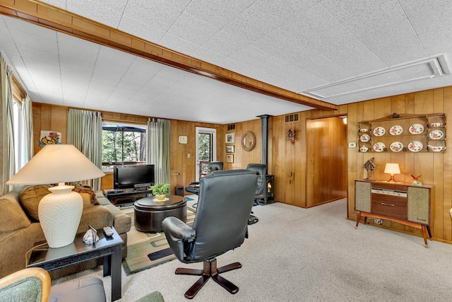 living room featuring a wood stove, light colored carpet, and wooden walls