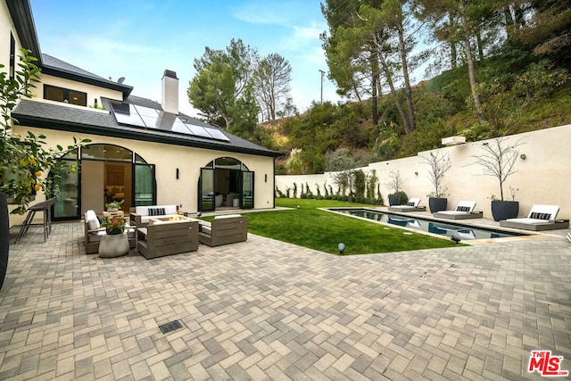 rear view of house featuring outdoor lounge area, a fenced in pool, a patio, and solar panels