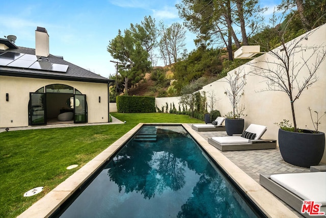 view of pool with a patio and a lawn