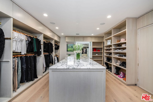 walk in closet with light hardwood / wood-style flooring