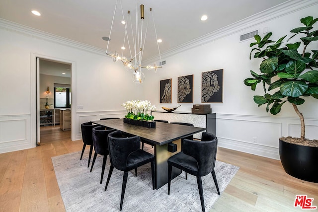 dining space with ornamental molding and light hardwood / wood-style floors