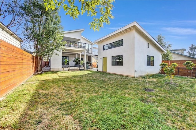 rear view of house featuring a balcony and a lawn