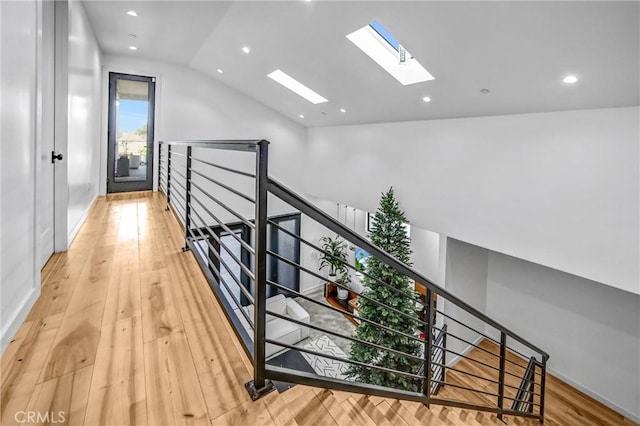 hallway with lofted ceiling with skylight and hardwood / wood-style floors