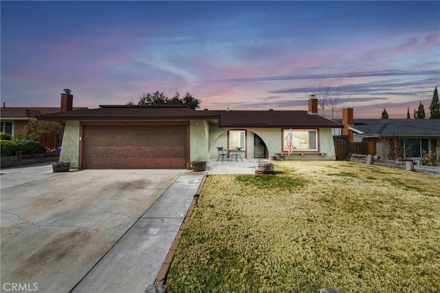 ranch-style home featuring a garage, a lawn, and a patio area