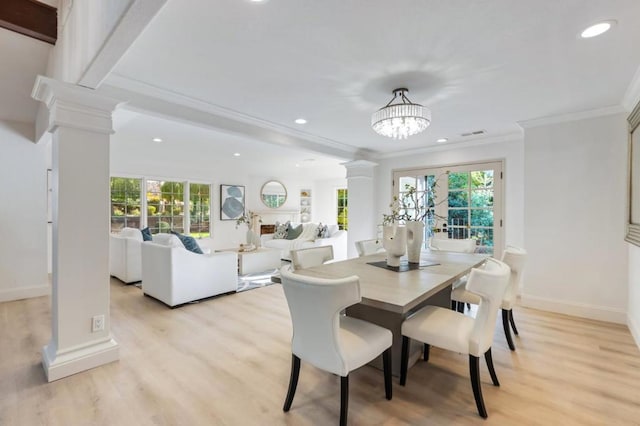 dining area featuring crown molding, light hardwood / wood-style floors, a healthy amount of sunlight, and ornate columns