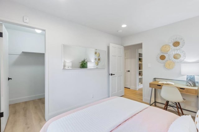 bedroom with a walk in closet and light wood-type flooring