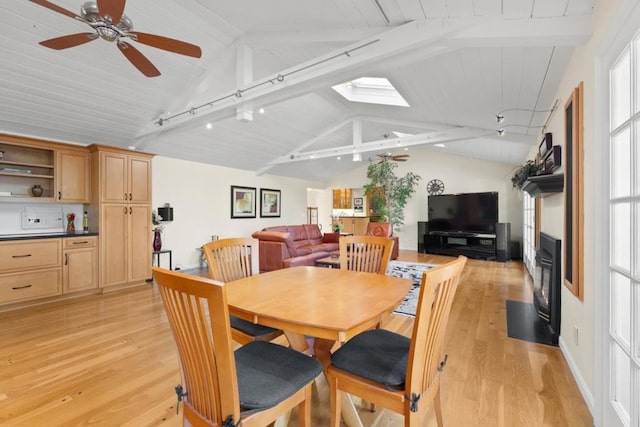 dining area with lofted ceiling with skylight, light hardwood / wood-style floors, and ceiling fan