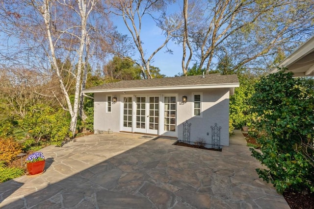 back of house featuring french doors, an outdoor structure, and a patio