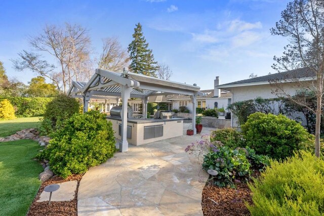 view of patio with exterior kitchen and a grill