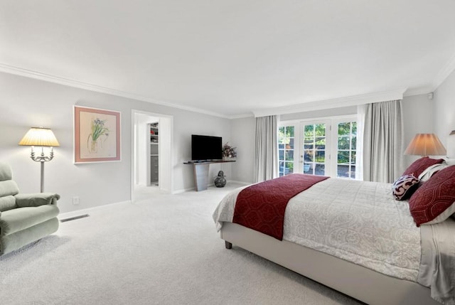 bedroom with crown molding, a walk in closet, carpet flooring, and french doors