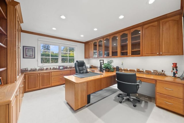 carpeted home office featuring crown molding and built in desk