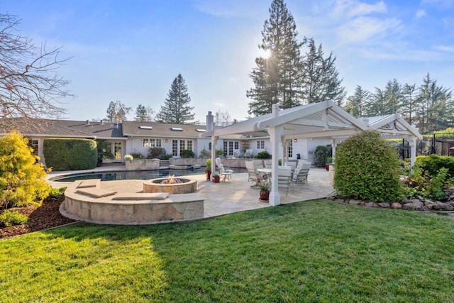 rear view of property featuring a yard, a patio area, and a fire pit