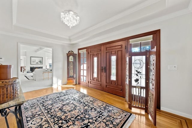 entryway featuring ornamental molding, hardwood / wood-style floors, a chandelier, and a tray ceiling