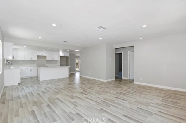 unfurnished living room featuring sink and light hardwood / wood-style floors