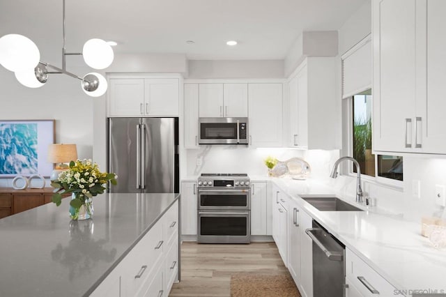 kitchen featuring decorative light fixtures, white cabinetry, sink, backsplash, and high end appliances