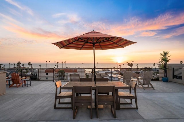 patio terrace at dusk featuring a water view